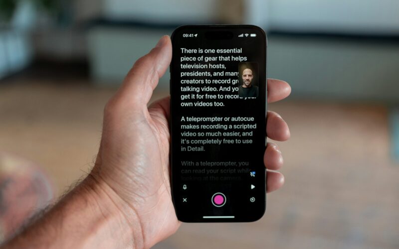 Hånd der holder smartphone med teleprompter-app åbent under videooptagelse
